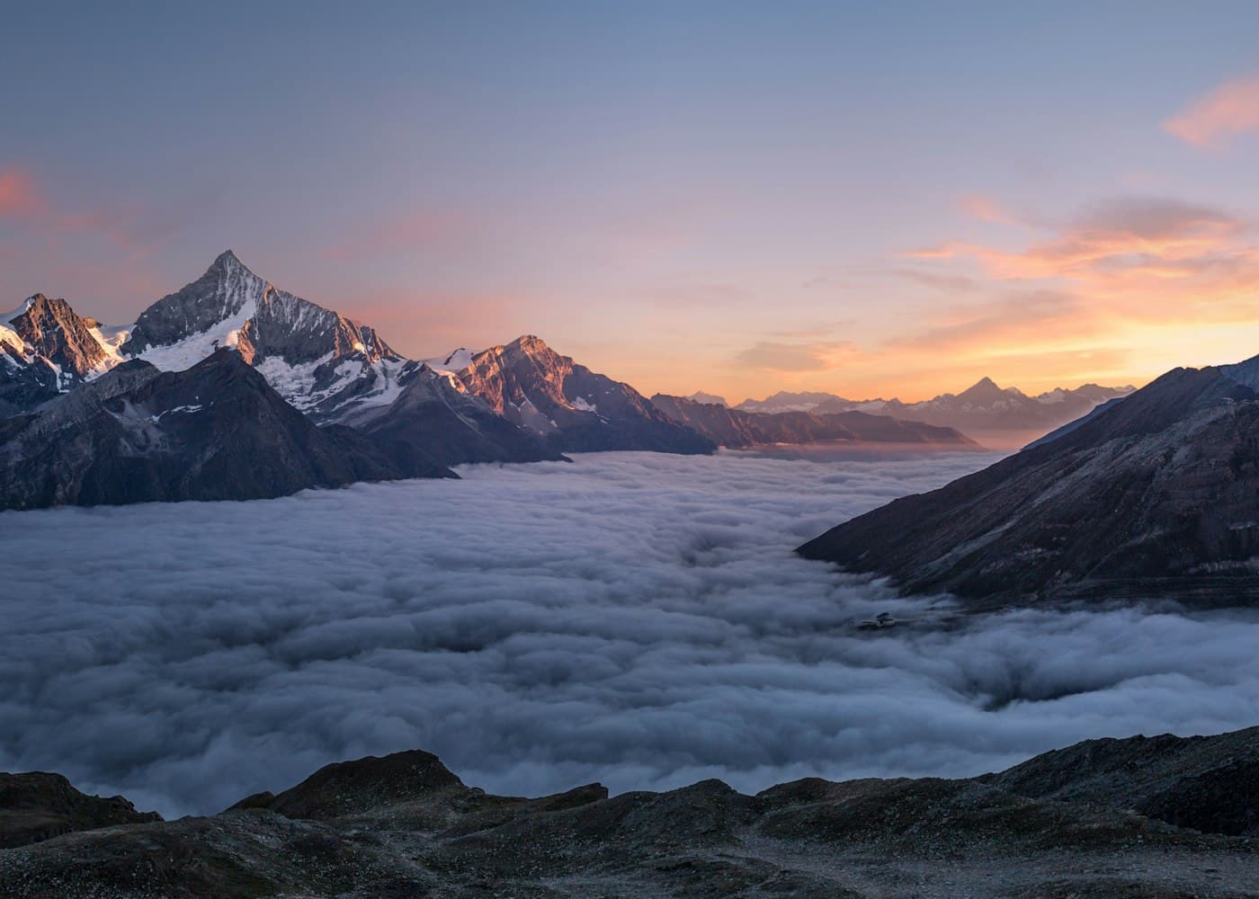A mountain range at sunrise above the clouds